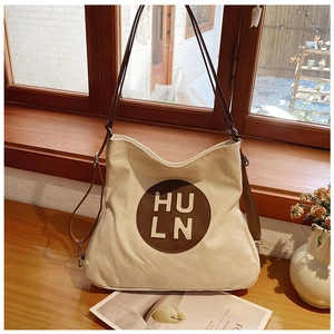 Detailed close-up of cream canvas tote bag with embossed HULN logo and leather strap