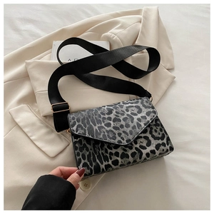 Detail of the leopard print crossbody bag with a wide strap on a beige blazer