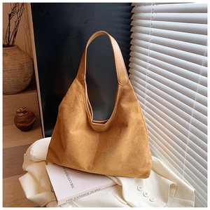 Detailopname van karamelkleurige suède hobo tas met fijne stiksels en artistiek licht