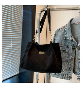 Détail du grand sac cabas en velours côtelé noir avec étiquette Fashion et chaîne