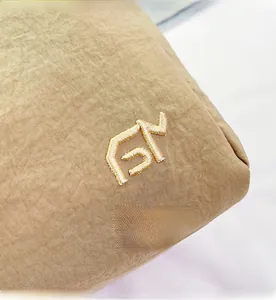 Detailed close-up of khaki shoulder bag showing high-quality embroidery logo and fabric texture