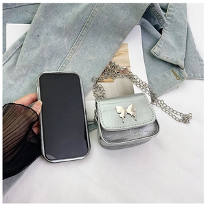 Silver mini crossbody bag with butterfly hardware shown against a smartphone for size reference