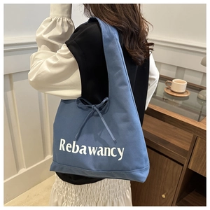 Detailoverzicht van de blauwe canvas tas met witte letters en strikdecoratie aan zijkant