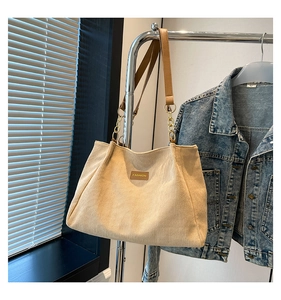 Détail du sac cabas en velours côtelé avec étiquette en cuir et bandoulière chaîne
