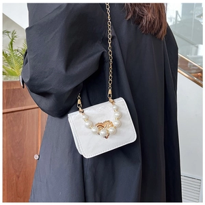Detailed shot of white glossy mini crossbody bag with pearl handle and gold heart clasp