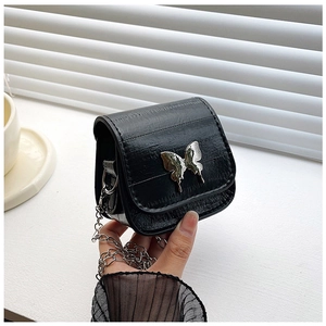 Close-up of black mini crossbody bag with silver butterfly metal buckle and chain strap