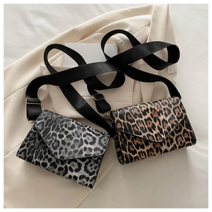 Flat lay of leopard print crossbody bags with wide nylon straps on a white blazer