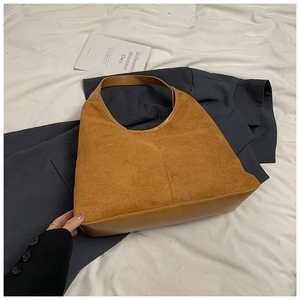 Detail van caramel suede hobo tas met contrast tussen mat en glad leer op de schouderband