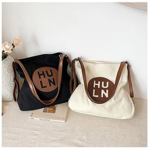 Detail of minimalist canvas tote bags with leather straps and HULN embossed patch