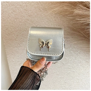 Close-up of silver mini crossbody bag with butterfly clasp and fine metal chain strap