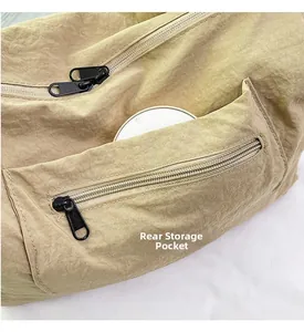 Detail of a khaki nylon bag showing a rear storage pocket with a black metal zipper