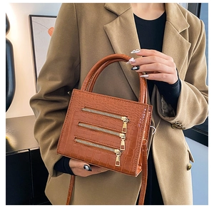 Detailed view of brown crocodile-pattern handbag with stylish metal zipper accents