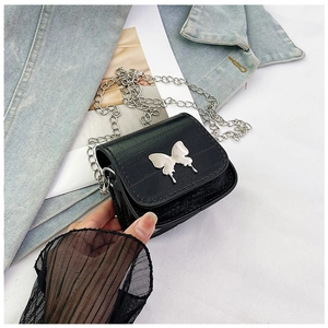 Detail of black crocodile texture mini bag featuring silver butterfly and chain strap