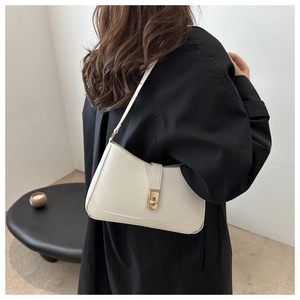 Minimalist cream white baguette bag with golden buckle shown on shoulder for daily wear
