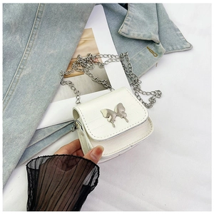 Detailed macro of a white mini handbag with crocodile pattern and silver butterfly buckle