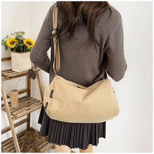 Detail of beige nylon crossbody bag with adjustable wide strap and fashion label on the side