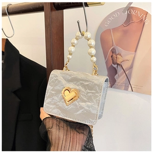 Macro shot of silver crinkled texture handbag with pearl handle and golden heart lock