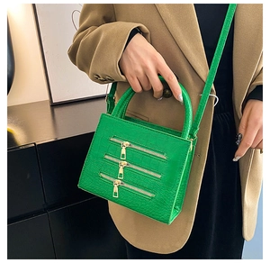 Detail of bright green textured tote featuring stylish gold zippers and crocodile pattern