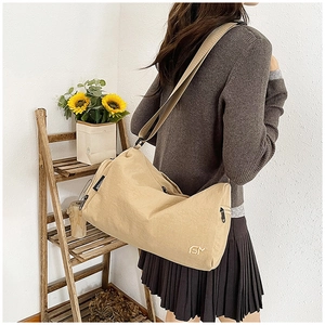 Detail of khaki shoulder bag featuring fashion label and metallic zipper closure