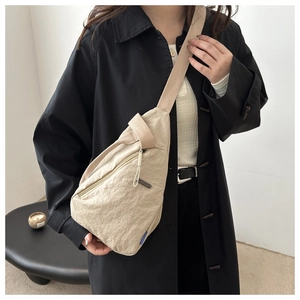 Detail of beige nylon crossbody bag showing the premium wrinkled texture and front zipper pocket