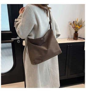 Brown high-density canvas shoulder bag shown on model with large trapezoidal structure