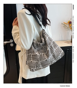 Detailed shot of large geometric canvas tote bag with adjustable black strap and fashion tag