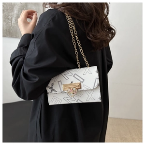 Chic white crossbody bag with black letter print and gold heart clasp detail on a model