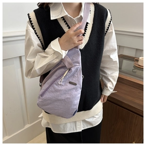 Detail of purple nylon chest bag showing crinkled texture and silver metal brand plaque