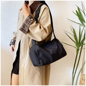 Detail view of black cylinder nylon crossbody bag with adjustable strap and fashion label