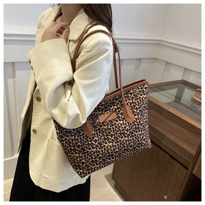 Detail of leopard print tote bag with brown leather handles and square logo patch