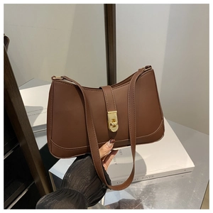 Detailed view of brown faux leather texture and gold twist lock on underarm bag