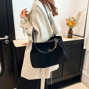 Sac cabas en velours côtelé noir avec bandoulière chaîne sur mannequin en trench-coat