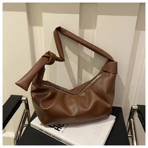 Detailed close-up of dark brown lychee texture leather with knot shoulder strap design