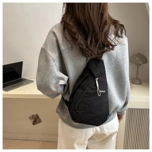 Rear view of a black nylon crossbody chest bag showing adjustable strap on a model