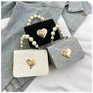 Detailed view of mini handbags featuring pearl handles and golden heart-shaped twist locks