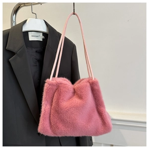 Pink plush faux fur shoulder bag with slender straps displayed on a black blazer
