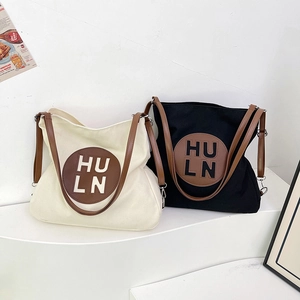 Minimalist large canvas tote bags with leather straps and embossed letters in black and cream