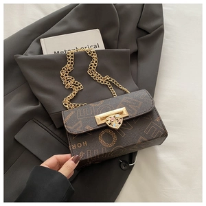 Detail of vintage brown printed crossbody bag featuring heart-shaped lock and gold chain