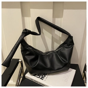Detailed macro view showing the premium lychee texture and knotted strap on the black bag