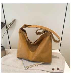 Detail of brown faux suede tote bag featuring a magnetic snap closure and knotted strap