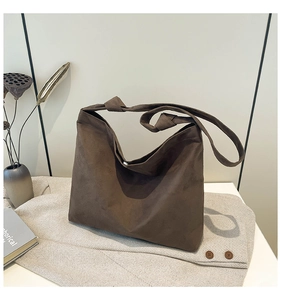 Close-up of deep brown suede tote bag with knotted strap details on beige textured fabric