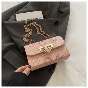 Detail of light pink leather crossbody bag with heart-shaped gold clasp and chain strap