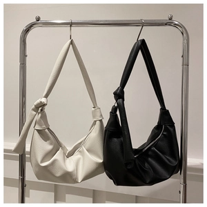 Detailed view of black and white pleated dumpling bags with knotted shoulder straps