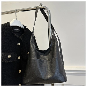 Vue détaillée du sac cabas en similicuir noir avec deux poches avant et texture douce