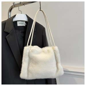Detailed view of white faux mink fur shoulder bag displayed against a black blazer