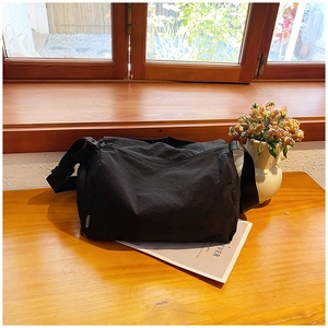 Close-up of black nylon tote bag with Fashion strap detail on a sunlit wooden table