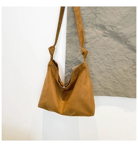 Close-up of caramel suede hobo bag featuring a knotted shoulder strap and magnetic closure