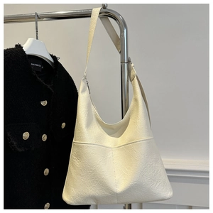 Détail du sac hobo beige avec poche avant suspendu à un support métallique chic