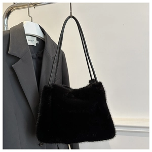 Close-up of black faux fur shoulder bag with leather straps on a minimalist garment rack