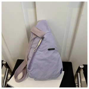 Detail of lavender nylon chest bag with metallic brand plate and smooth zipper texture